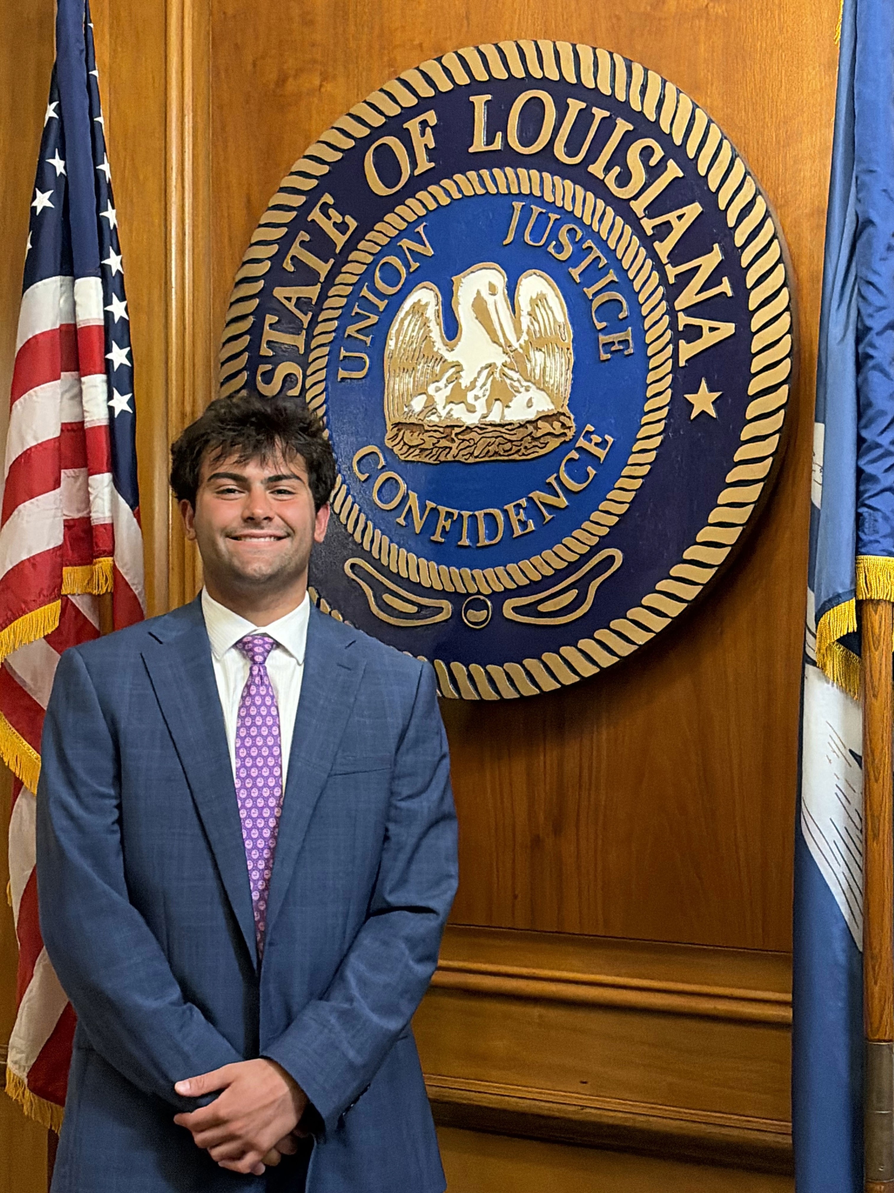 Headshot of boy in front of the Louisiana State symbol and American Flag