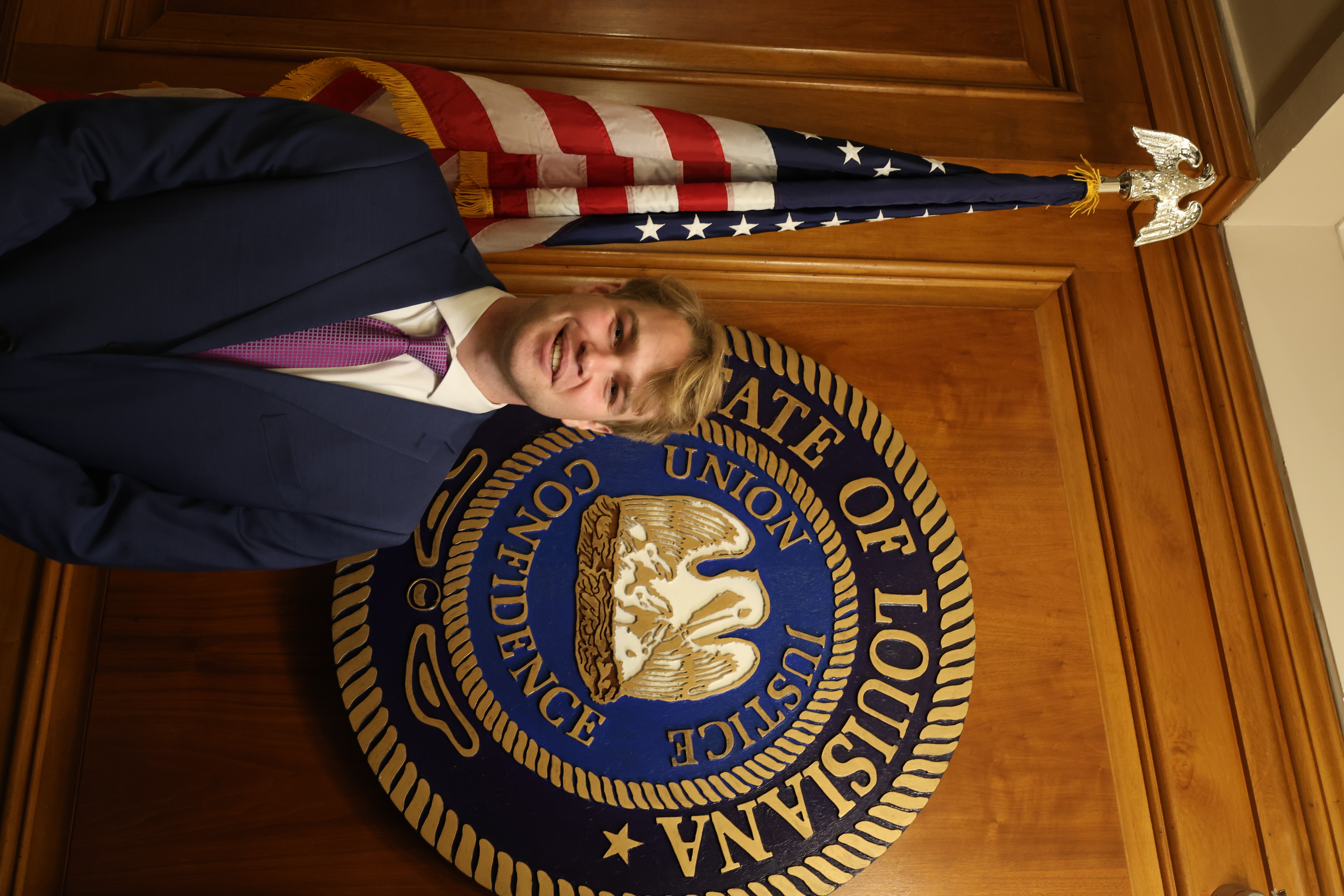 Headshot of boy in front of the Louisiana State symbol and American Flag